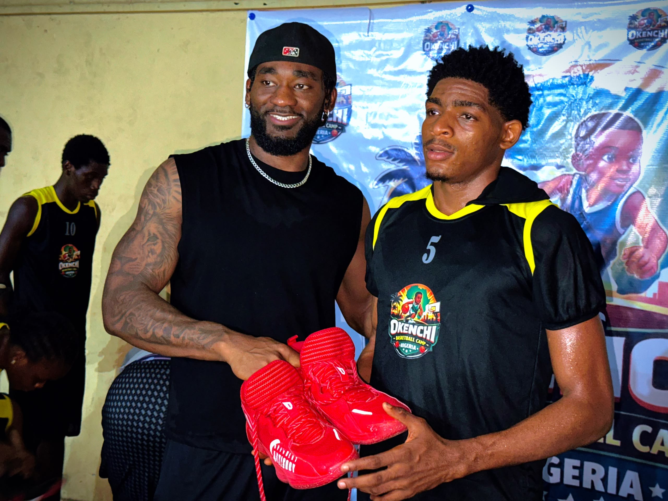 Eric Okenchi presenting red basketball shoes to a camper
