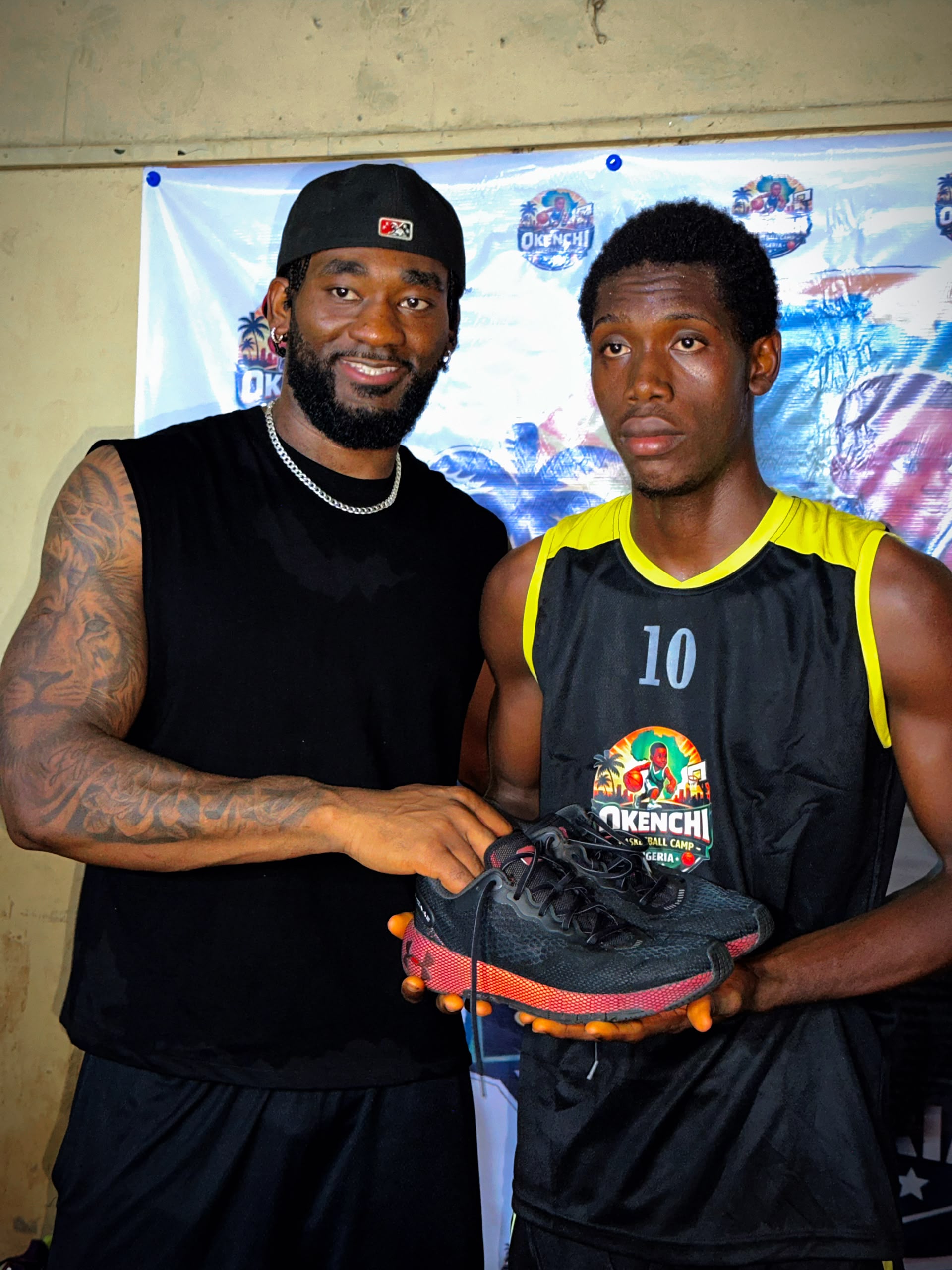 Eric Okenchi presenting basketball shoes to a camper wearing number 10