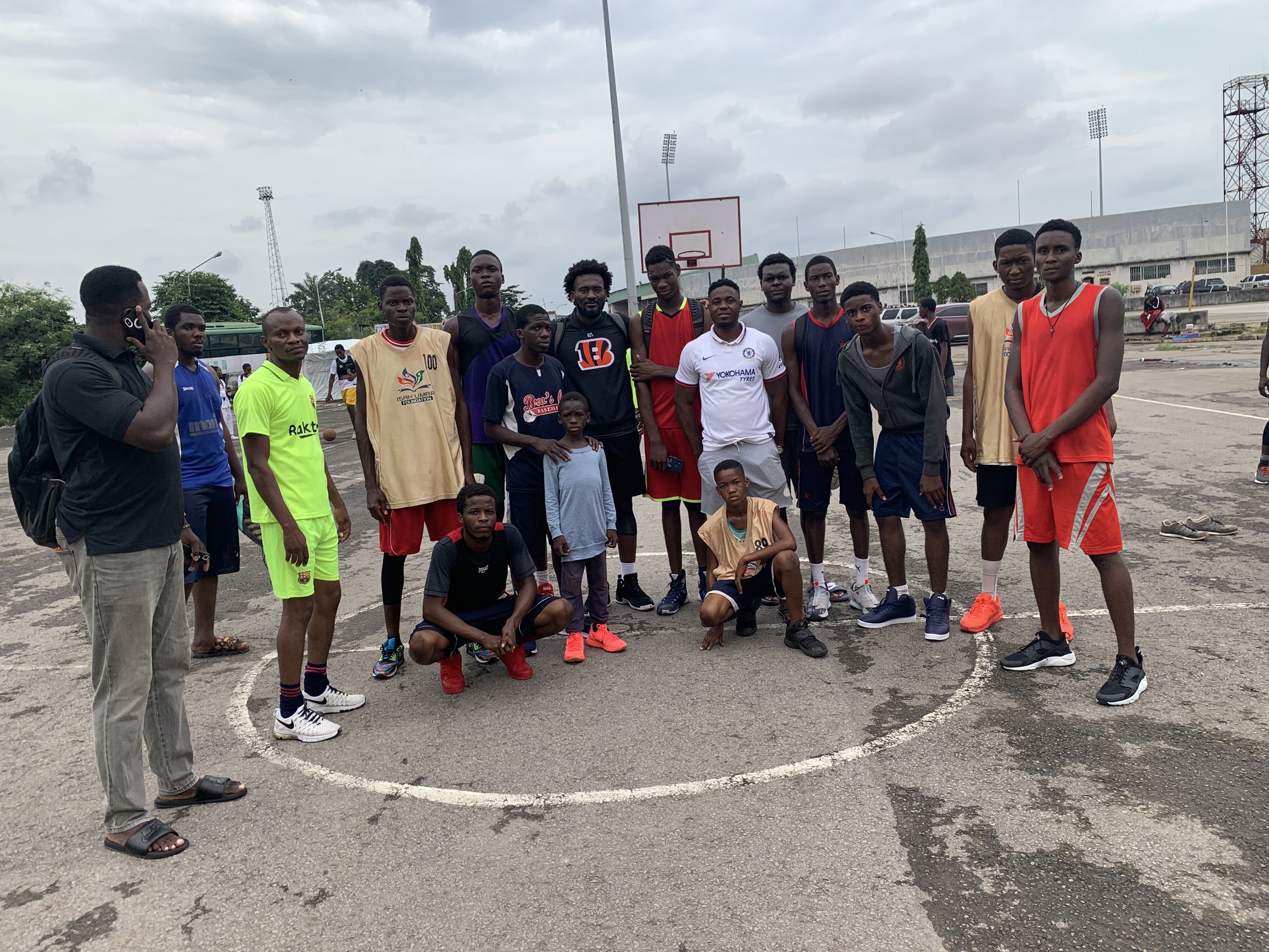Eric Okenchi with a group of players gathered on an outdoor basketball court