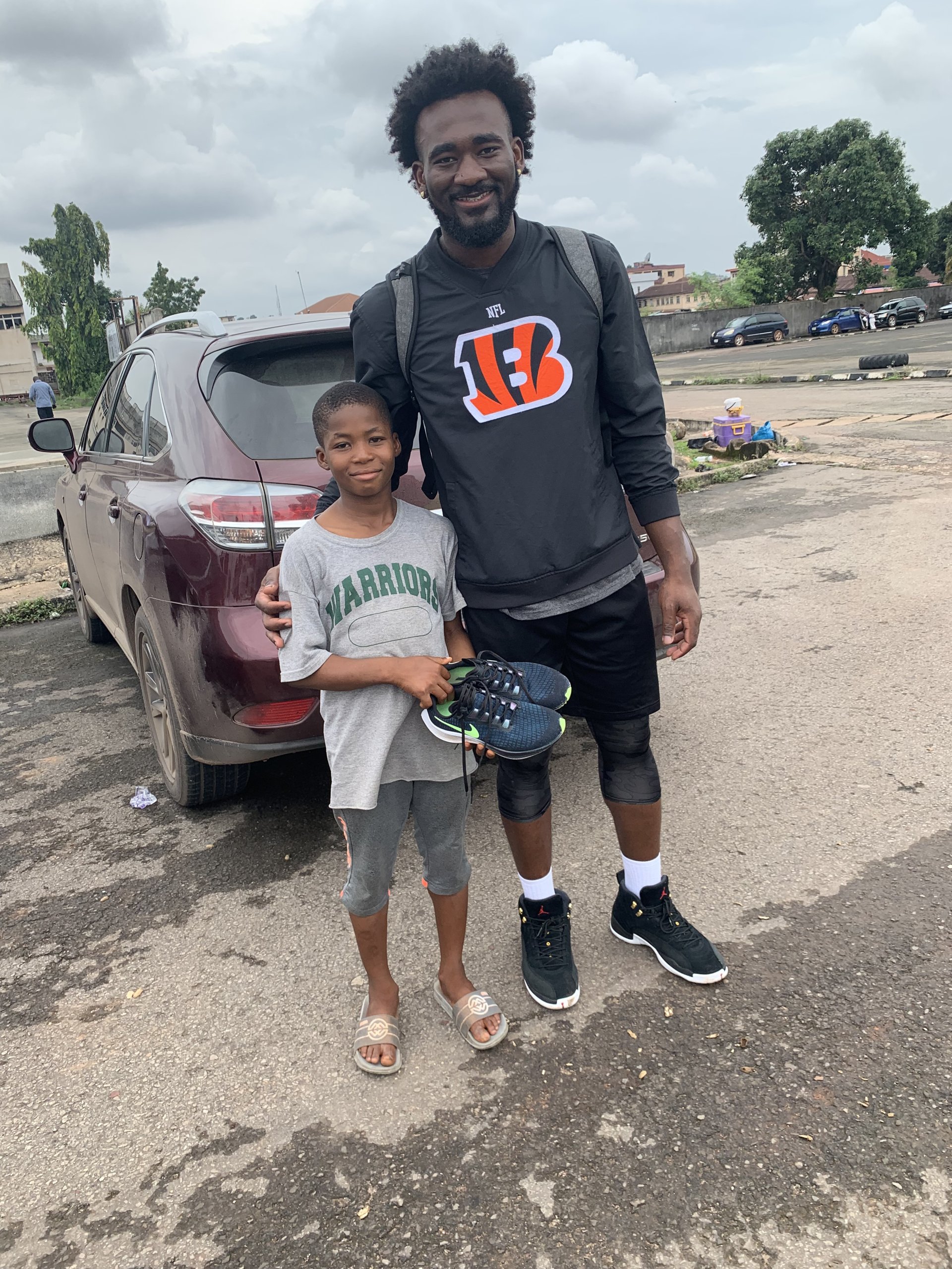 Eric Okenchi with a young camper holding a new pair of basketball shoes