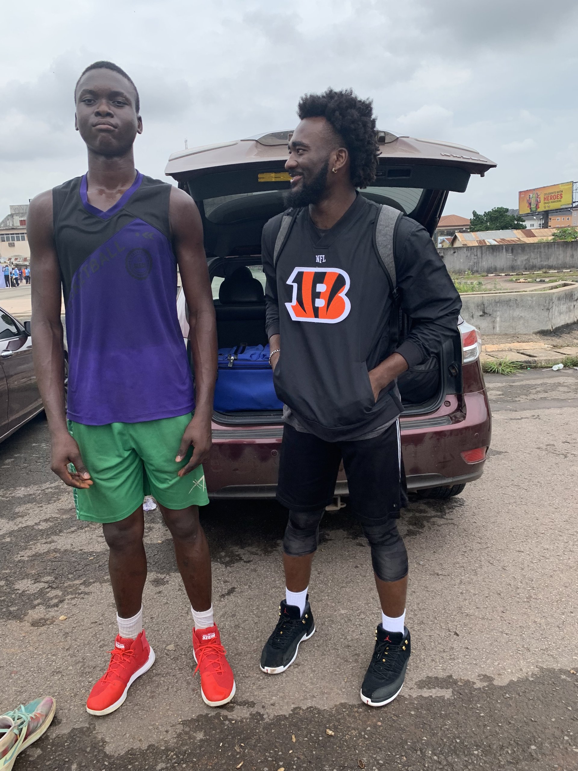 Eric Okenchi standing with a young player beside a car
